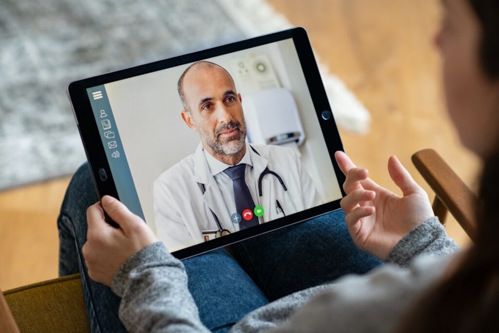 A person talking to a doctor in a video conference using a tablet.