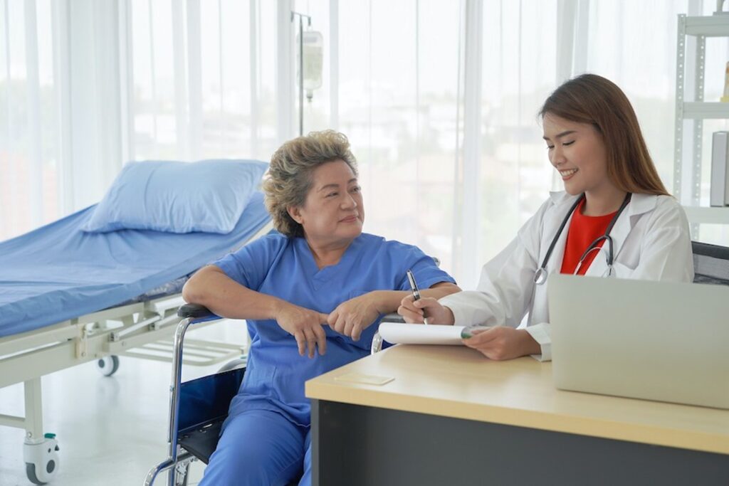 A patient listens to a health care worker go over data on a tablet