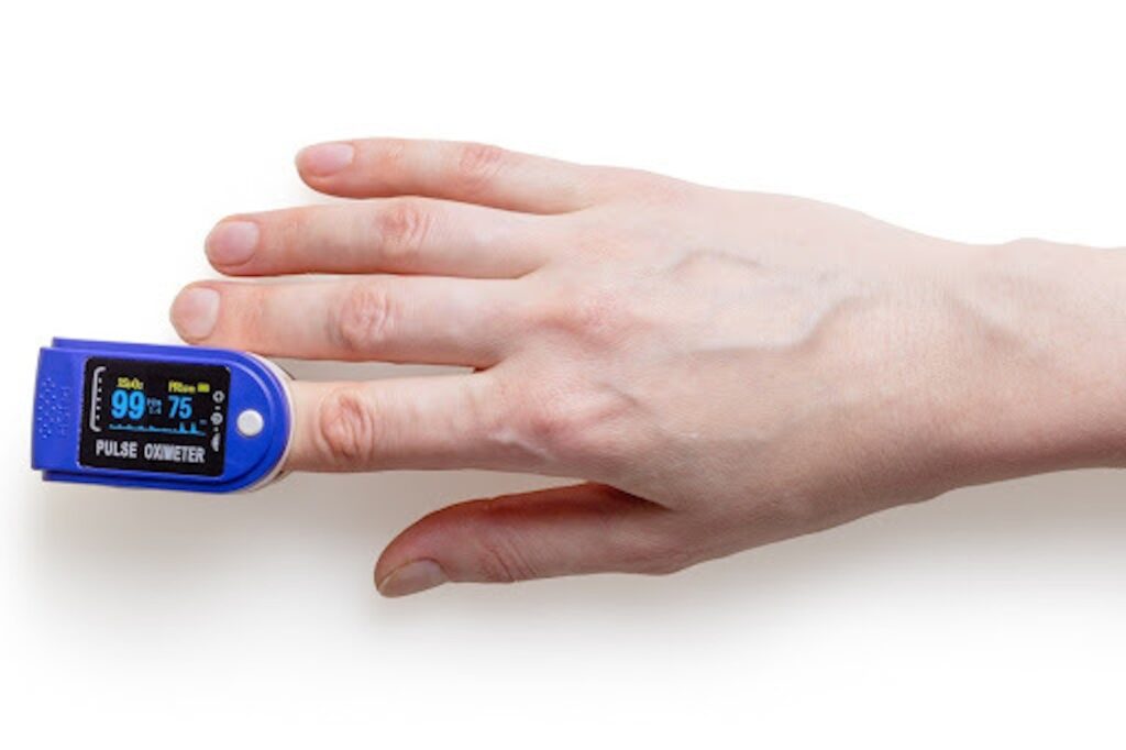 A pulse oximeter on a hand against a white background.