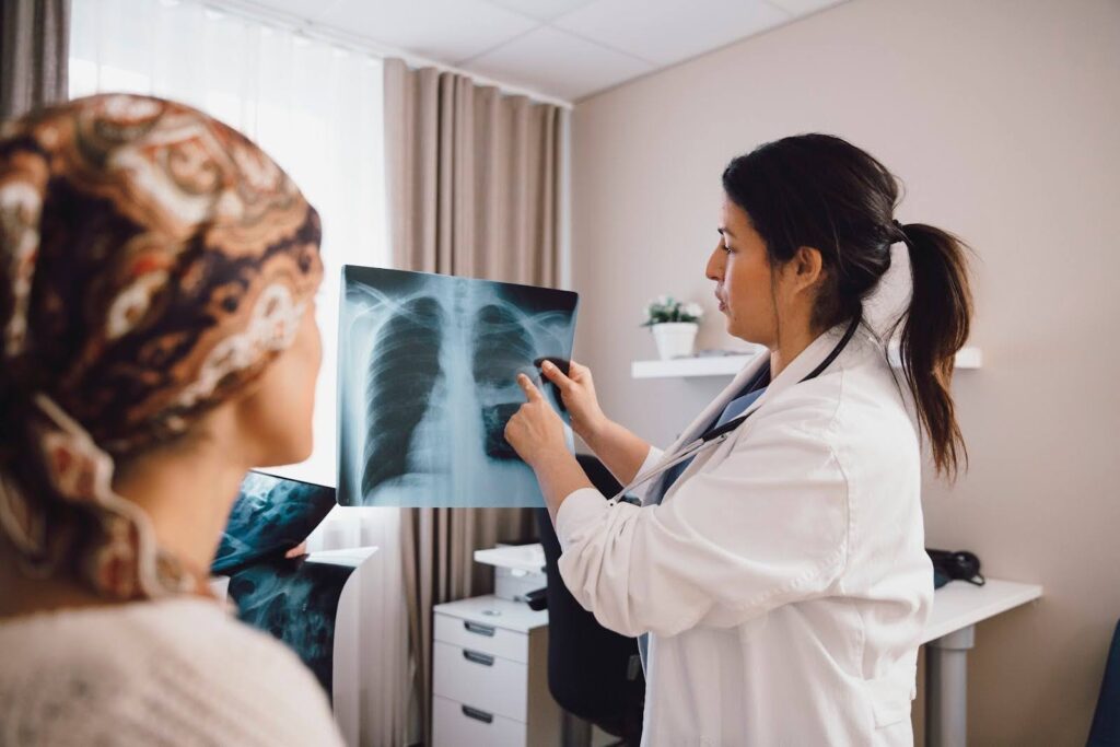 A physician assistant discusses the results of a lung X-ray with a patient.